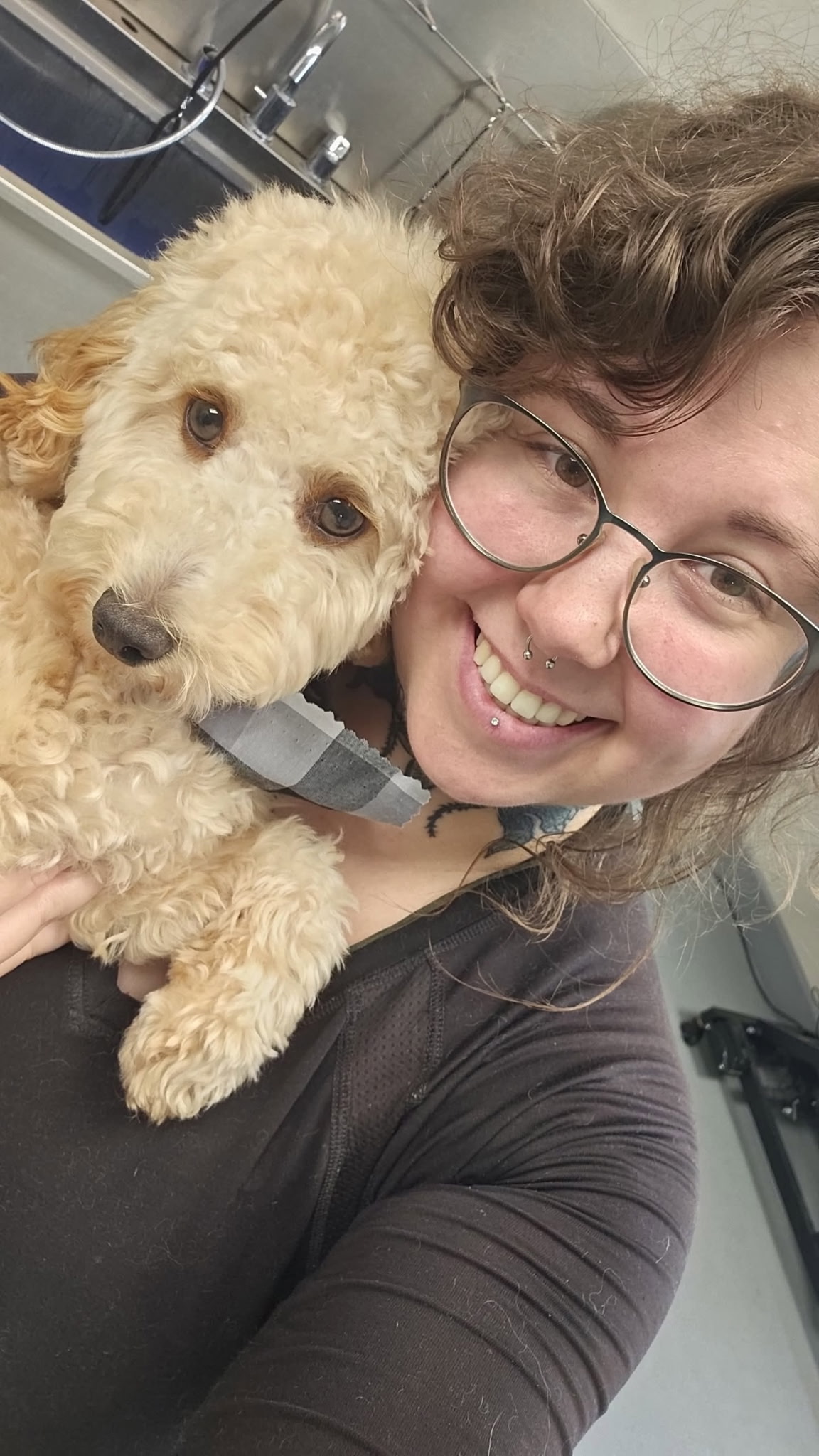 Katelyn smiles alongside a happy dog after a fresh grooming